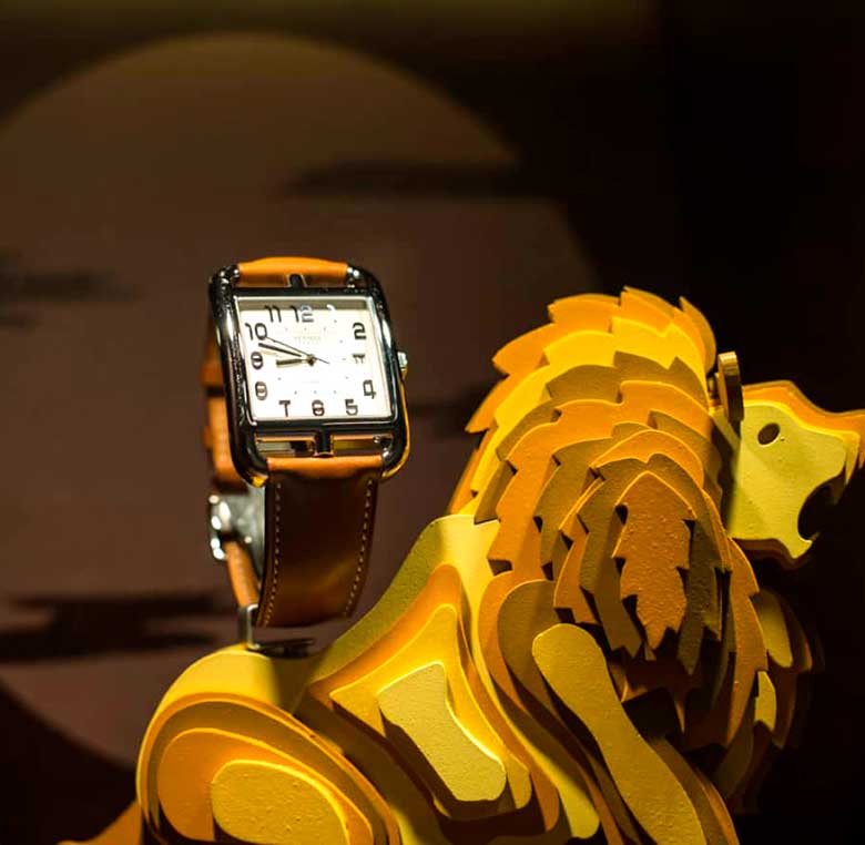 León de madera que expone un reloj para escaparate de Hermes